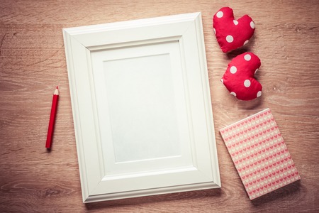 White photo frame small red hearts and pencil on wooden tableの写真素材