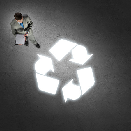 Top view of thoughtful businessman looking at glowing sign on concrete floorの写真素材