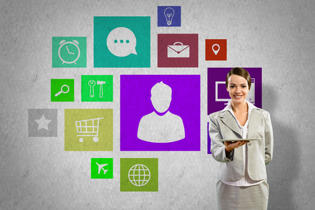 Businesswoman presenting tablet pc and color icons at backgroundの写真素材