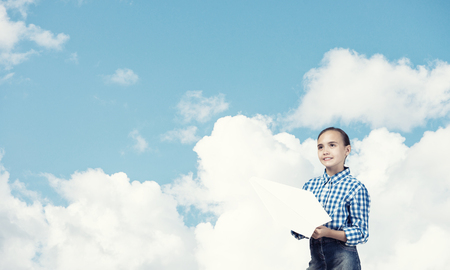 Adorable little girl holding paper plane outdoors on blue sky backgroundの写真素材