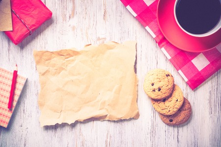 Sheet of paper coffee cup and cookies top view on wooden tableの写真素材