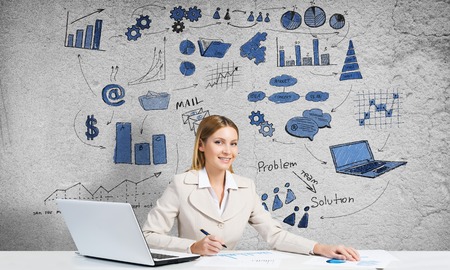 Young businesswoman with pen in hands thinking over her business planの写真素材