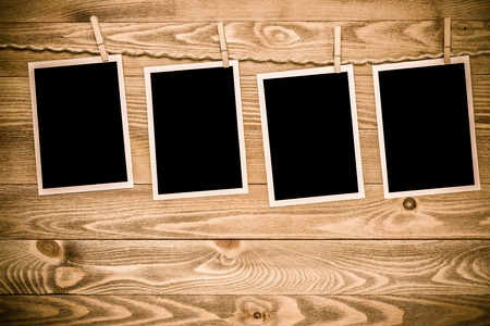 Blank photo frame hanging on rope on wooden textured backgroundの写真素材