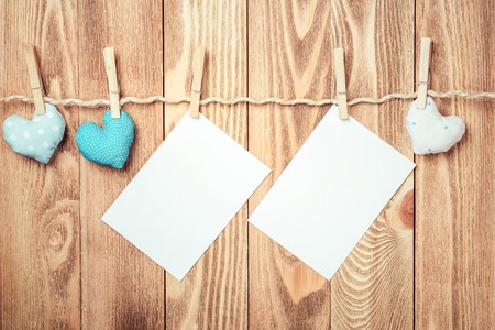 Blank sheet of paper hand made heart pinned to rope on wooden backgroundの写真素材