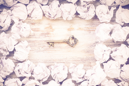 Vintage key among many balls of crumpled paperの写真素材