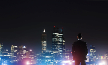 Elegant businessman with suitcase looking at night cityの写真素材