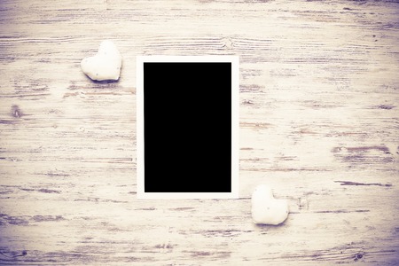 Blank photo frame and love hearts on wooden table