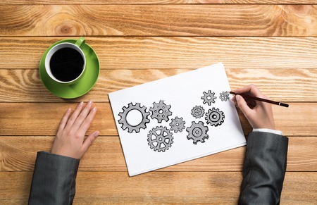 To view of businesswoman hands drawing on paper sheet gears mechanismの写真素材