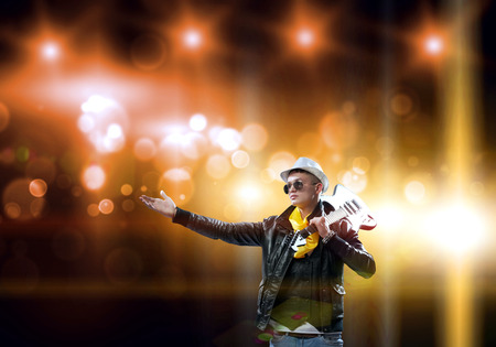 Young man rock musician in lights of stageの写真素材