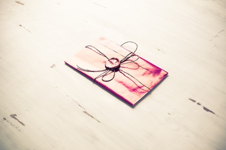 Pink letter envelope with wax seal on wooden surface