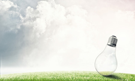 Electric light bulb against summer cloudy skyの写真素材