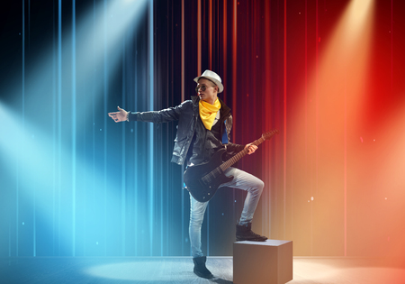 Young man rock musician in lights of stageの写真素材