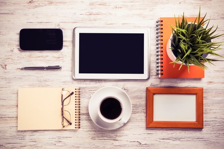 Still life photo of tablet notepad coffee glasses on wooden tableの写真素材