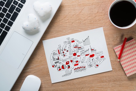 Keyboard notepad with sketches and coffee cup on wooden deskの写真素材