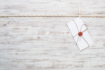 Envelope hanging on rope on wooden background