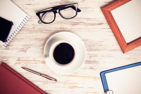 Still life photo of tablet notepad coffee glasses on wooden tableの写真素材