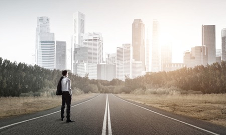 Elegant businessman on road standing with back and looking aheadの写真素材
