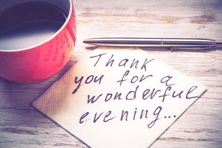 Cup of coffee and napkin with message on wooden tableの写真素材