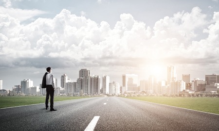 Elegant businessman on road standing with back and looking aheadの写真素材