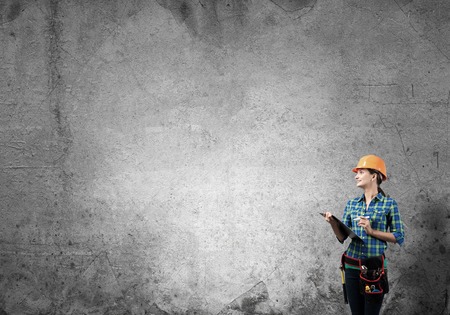 Engineer woman with folder and sketches of construction project on wallの写真素材