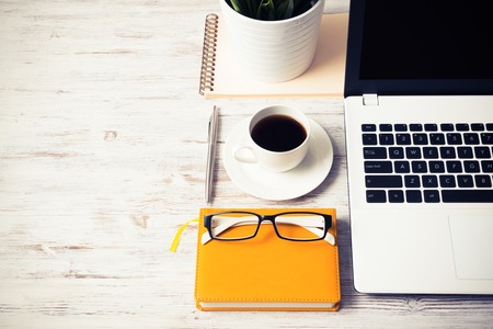 Still life photo of laptop notepad coffee glasses and other stuff on wooden tableの写真素材