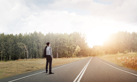 Elegant businessman on road standing with back and looking aheadの写真素材