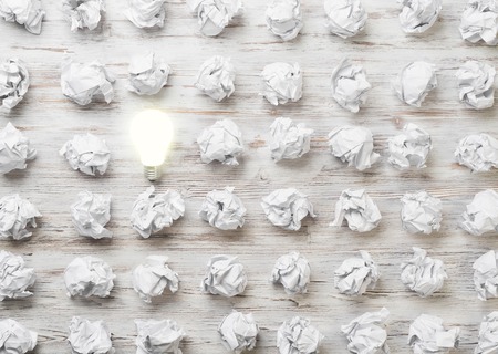 Many balls of crumpled paper and glowing light bulbの写真素材