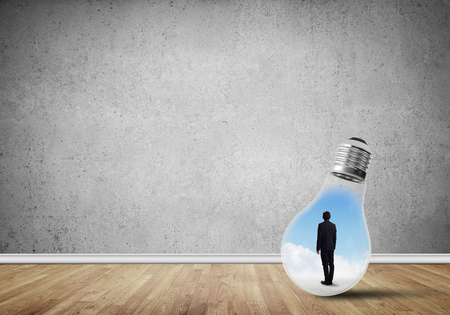 Businessman inside of light bulb in empty concrete roomの写真素材