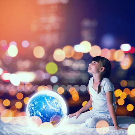 Cute girl in bed looking at glowing Earth planet. Elements of this image are furnished by NASAの写真素材