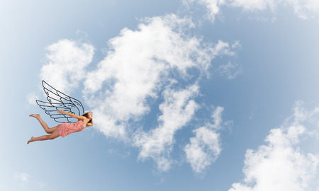 Young woman flying high in blue skyの写真素材