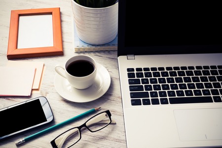 Still life photo of laptop notepad coffee glasses and other stuff on wooden tableの写真素材