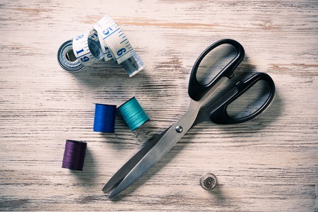 Old scissors bobbins threads and tape on wooden tableの写真素材