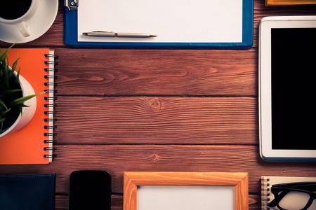 Still life photo of tablet notepad coffee glasses and other stuff on wooden tableの写真素材