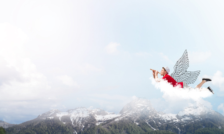 Young cheerful man flying high in sky and playing fifeの写真素材