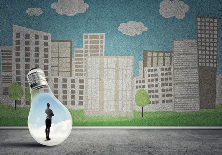 Businesswoman inside light bulb against city drawn conceptの写真素材