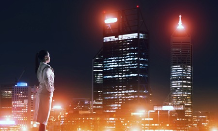 Rear view of elegant businesswoman viewing lights of night cityの写真素材