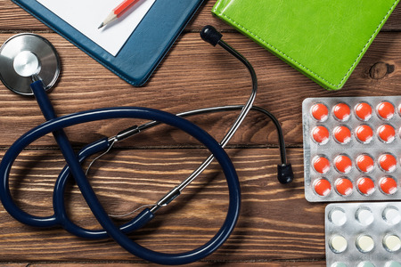 Doctors wooden table with tablet stethoscope and other stuffの写真素材