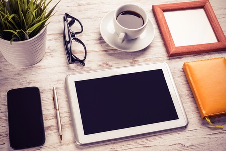 Still life photo of tablet notepad coffee glasses on wooden tableの写真素材