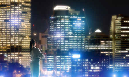 Rear view of elegant businesswoman viewing lights of night cityの写真素材