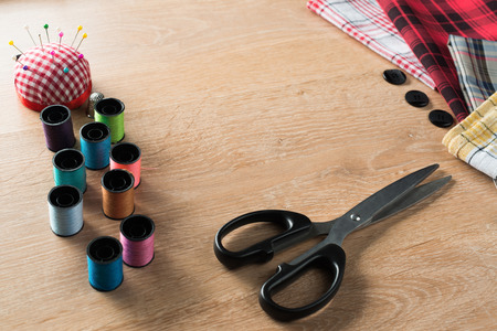 Old scissors bobbins threads material on wooden table