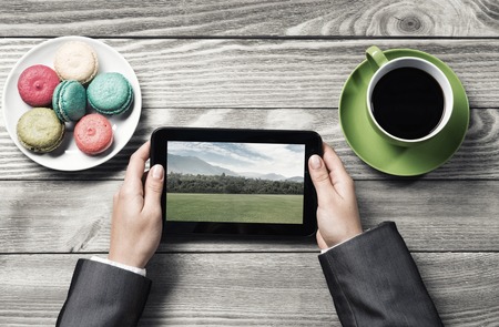 Top view of businesswoman sitting at wooden table and using tablet pcの写真素材