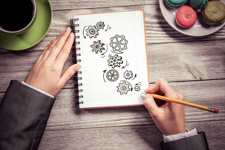 To view of businesswoman hands drawing in notepad gears mechanismの写真素材