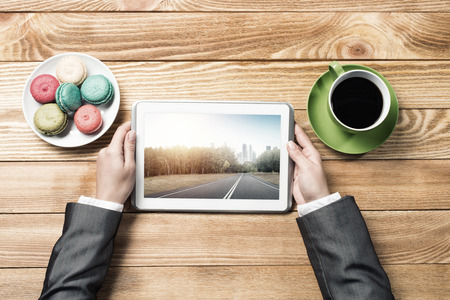 Top view of businesswoman sitting at wooden table and using tablet pcの写真素材