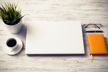 Still life photo of laptop notepad coffee glasses and other stuff on wooden tableの写真素材