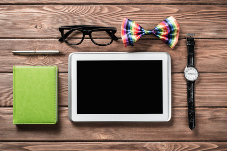 Tablet pc computer wallet eyeglasses bowtie and wristwatch on tableの写真素材