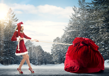 Santa woman pulling huge red gifts bagの写真素材