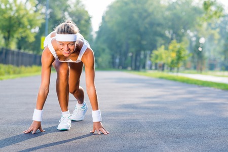 Young woman runner outdoor standing in start poseの写真素材