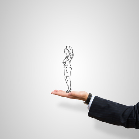 Drawn businesswoman in male palm on gray backgroundの写真素材