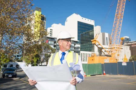 Construction engineer in hardhat with project in handsの写真素材