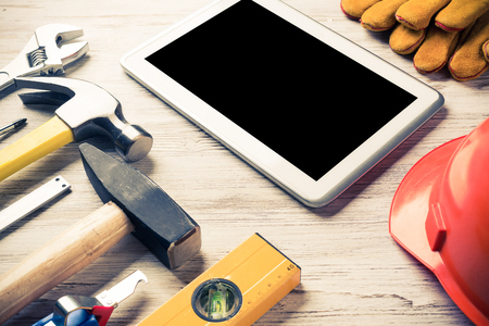 Set of industrial tools and tablet on wooden surfaceの写真素材